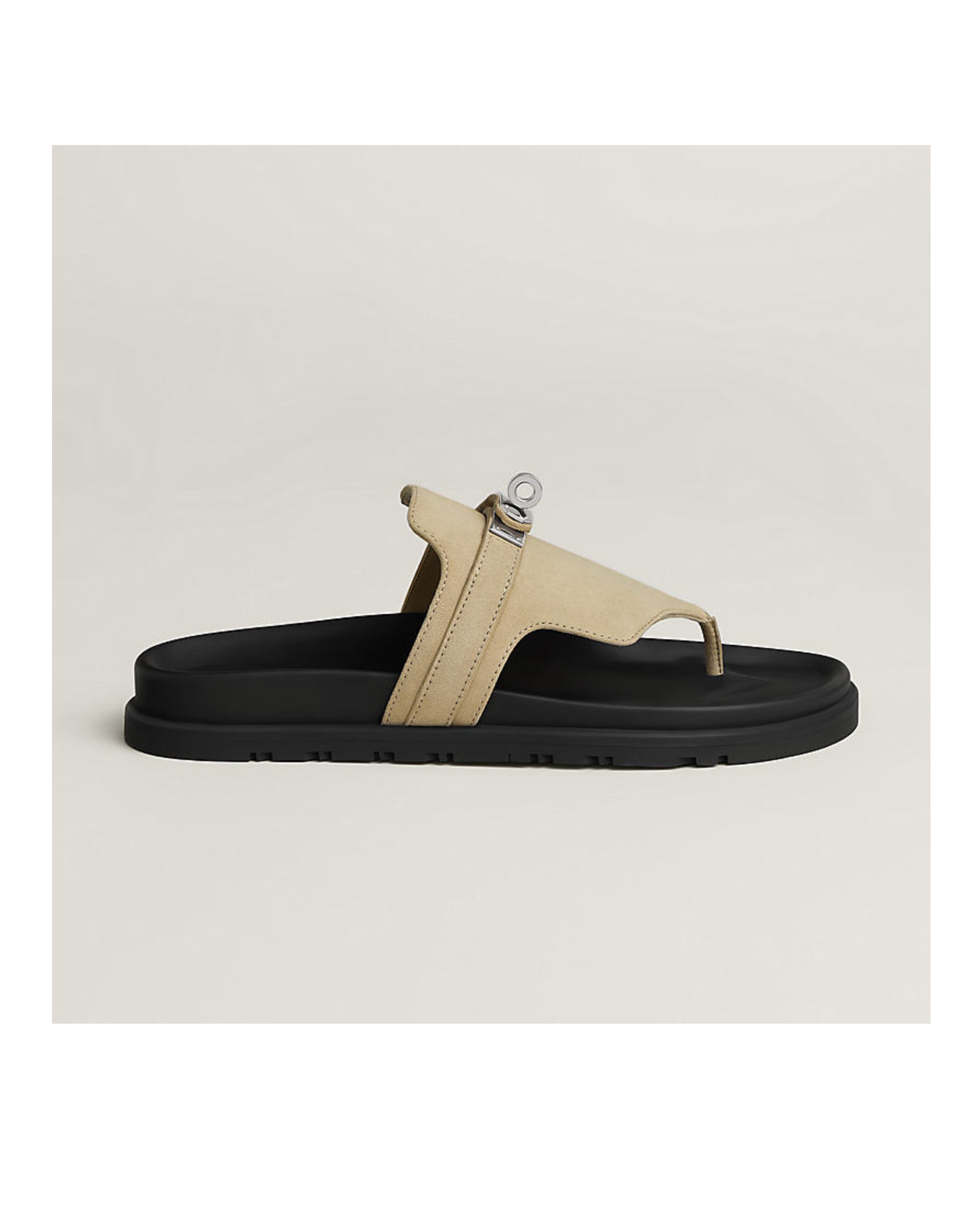 Beige sandal with black sole on a light beige background
