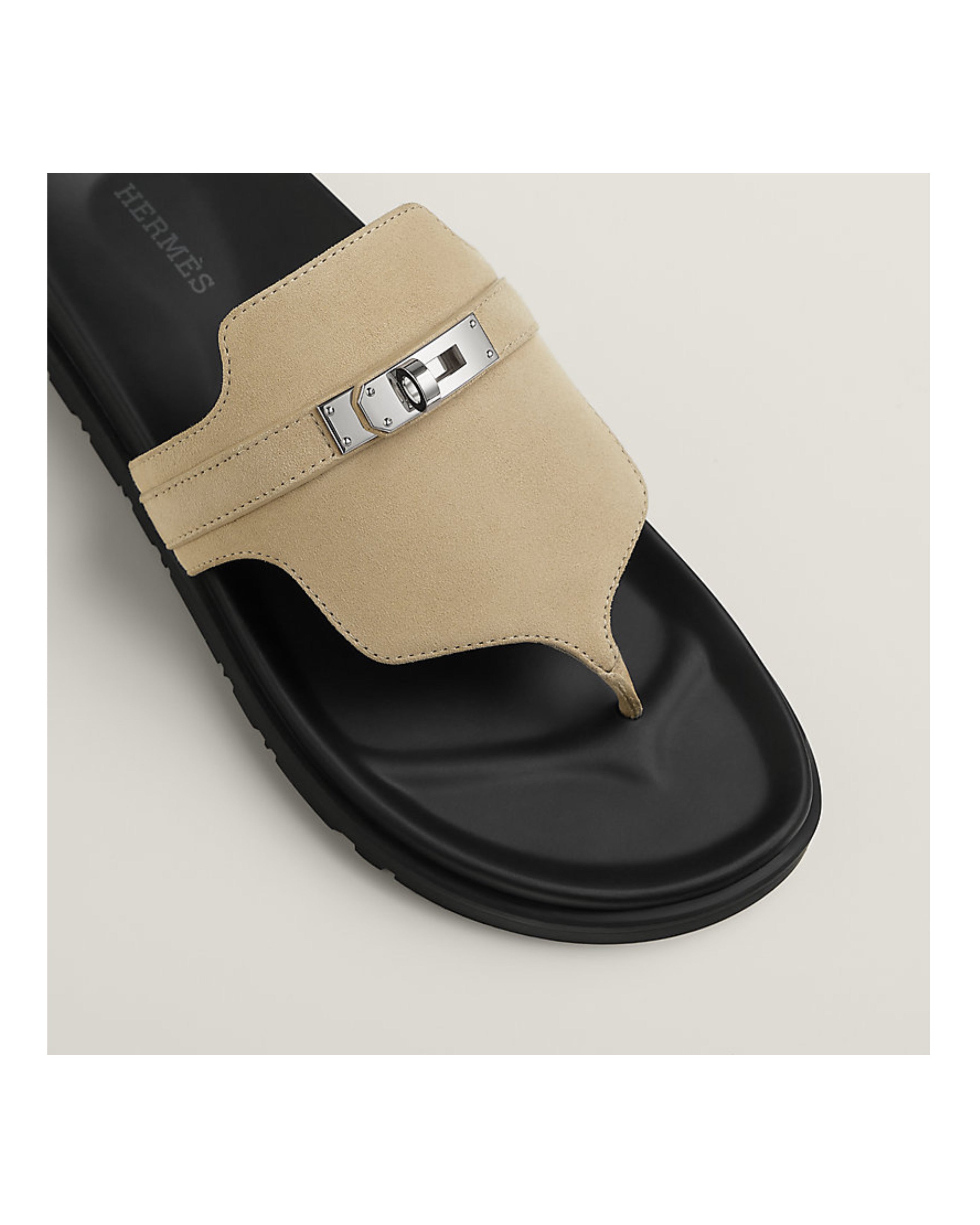 Beige sandal with black sole on a light beige background