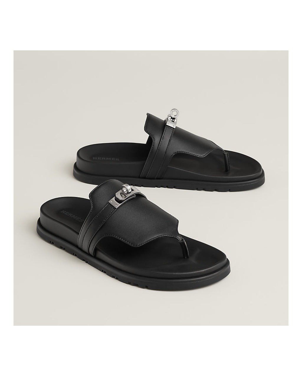 Black sandals with metallic accents on a light gray background