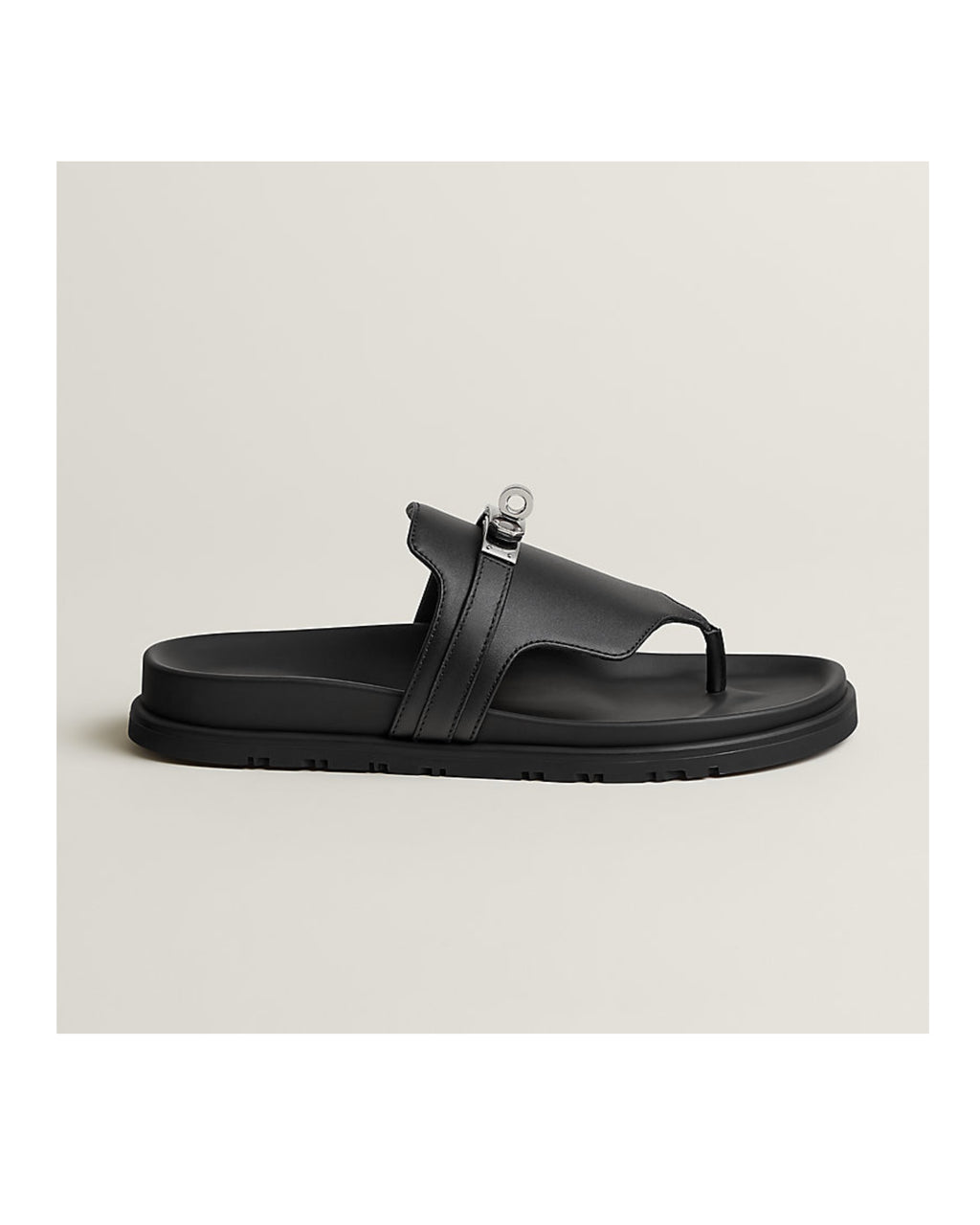 Black sandal with a unique strap design on a light beige background