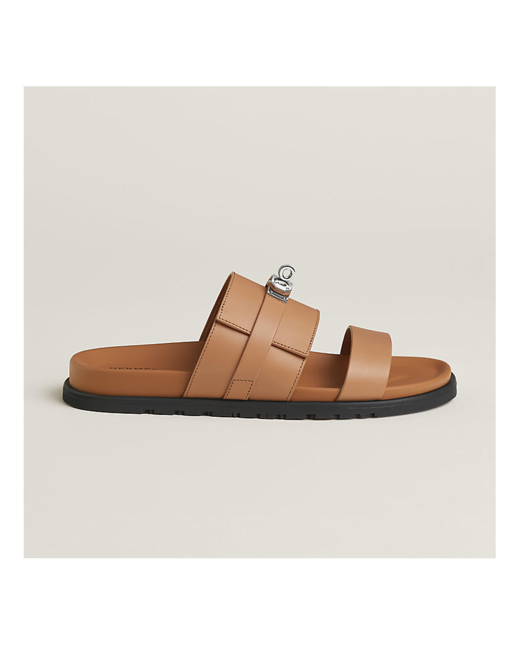 Tan sandal with a black sole on a light beige background