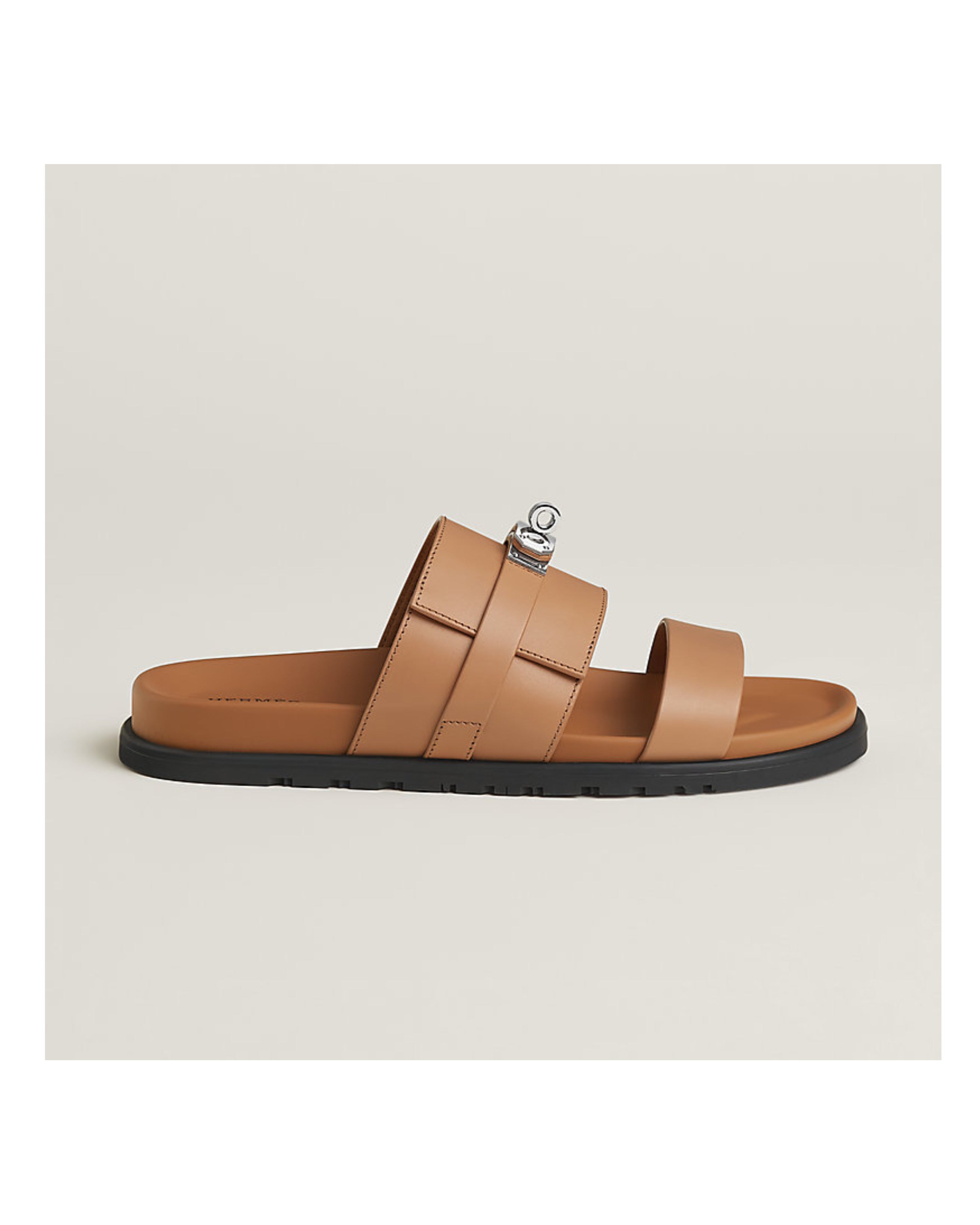 Tan sandal with a black sole on a light beige background