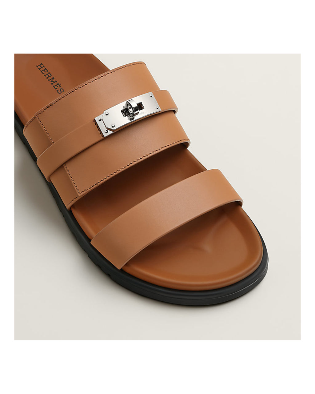 Brown sandal with a silver buckle on a beige background