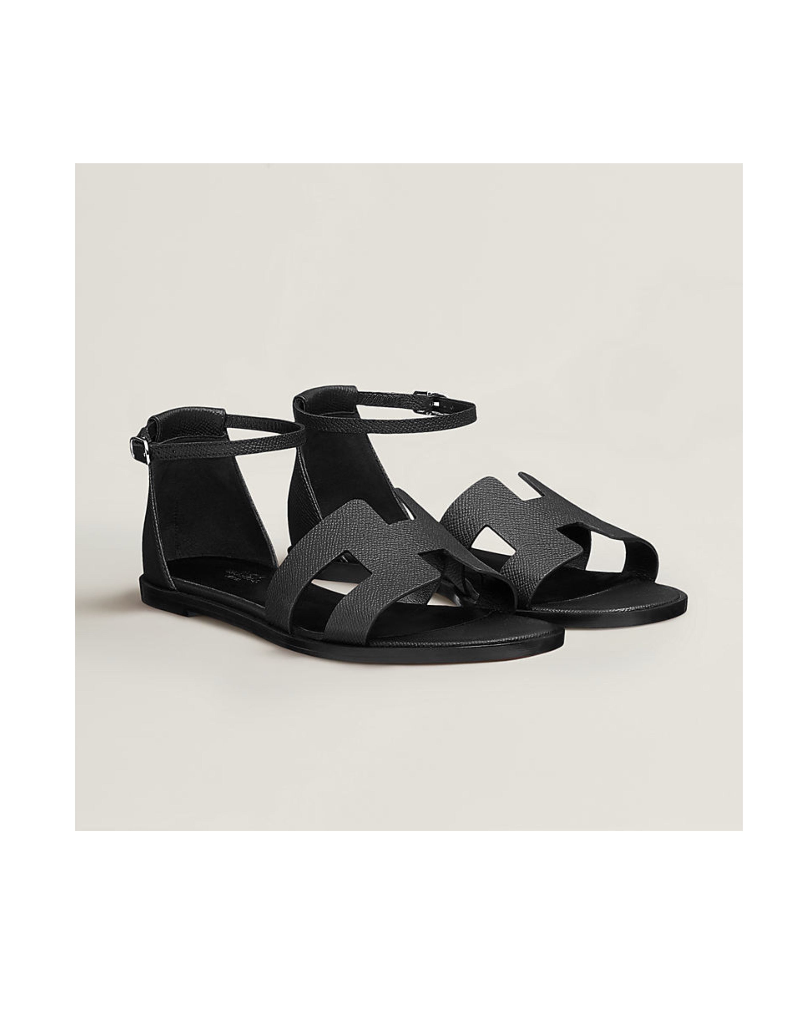 Black sandals with a minimalist design on a light beige background