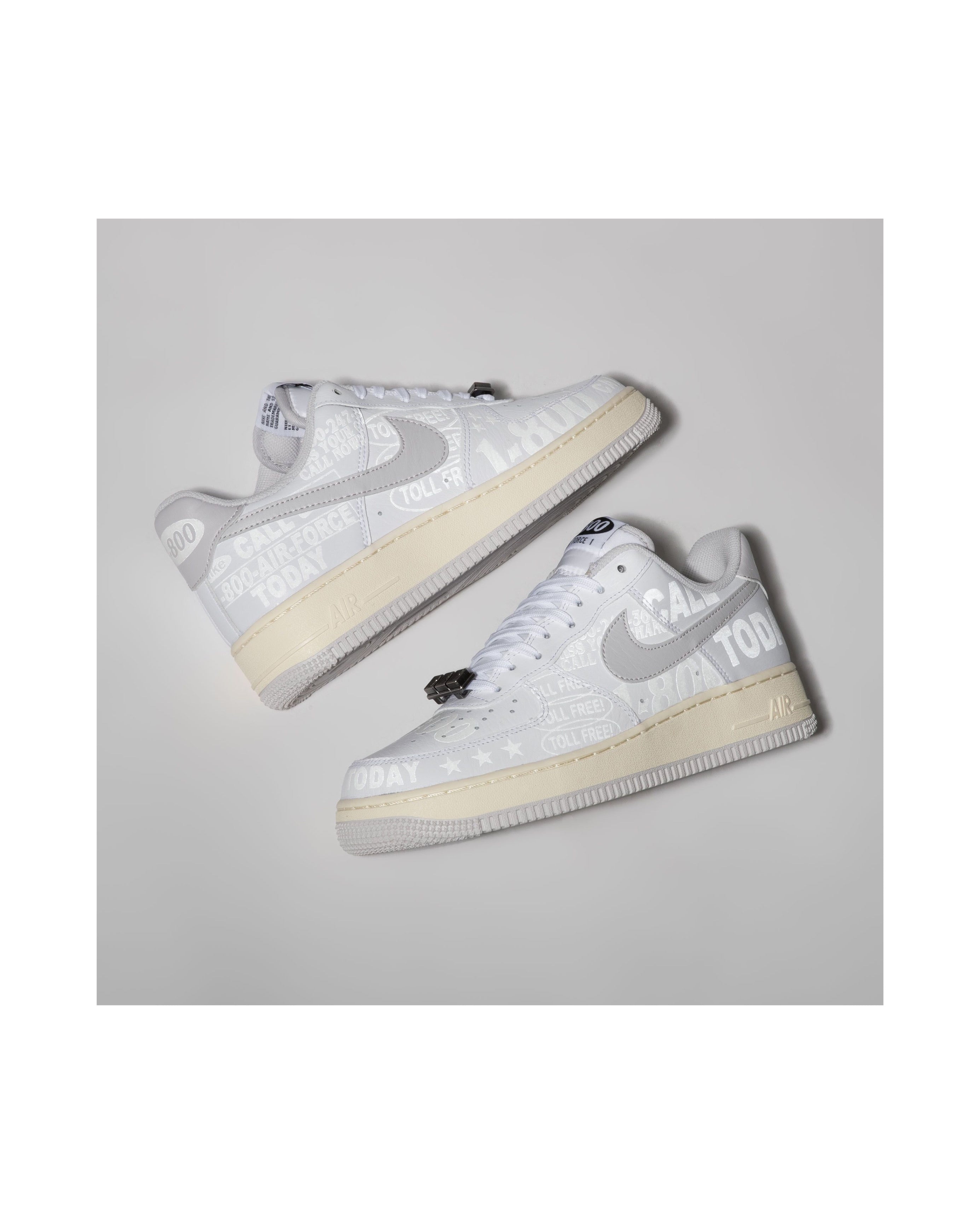 Pair of white sneakers with gray swoosh logo on a light gray background